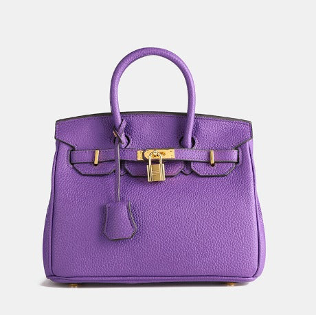 Image showing a woman holding an elegant handbag with a sleek design, featuring gold hardware and a structured shape, paired with casual attire for a stylish, sophisticated look.