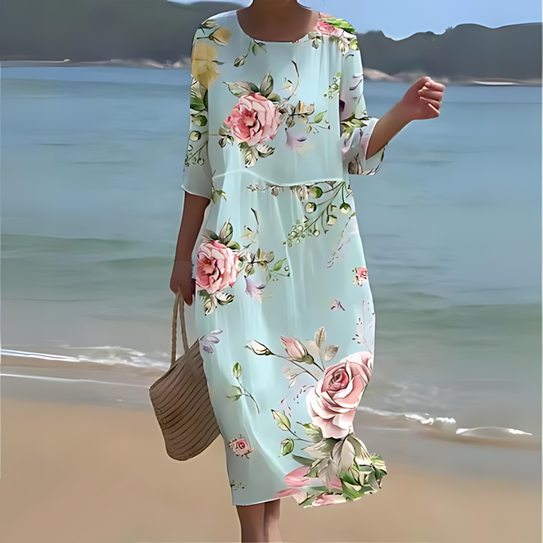 Elegant women's floral dress worn on the beach, paired with a woven handbag, perfect for summer outings and casual strolls.