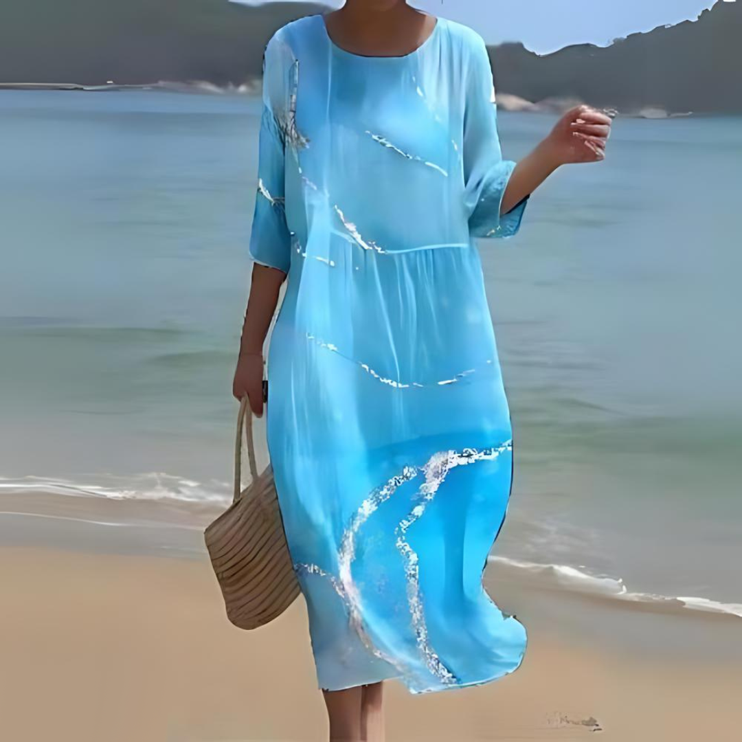 Elegant women's floral dress worn on the beach, paired with a woven handbag, perfect for summer outings and casual strolls.