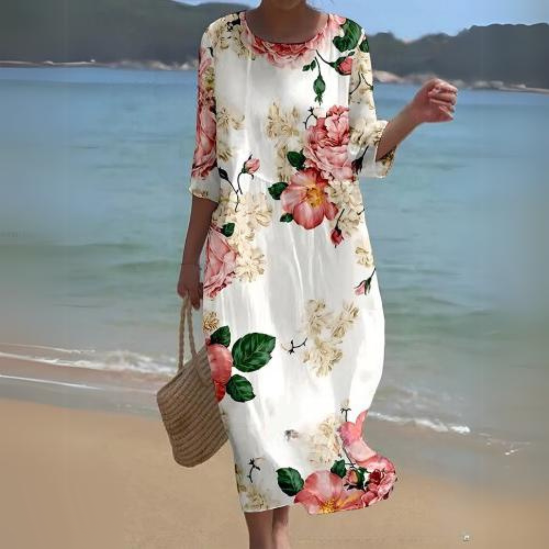 Elegant women's floral dress worn on the beach, paired with a woven handbag, perfect for summer outings and casual strolls.