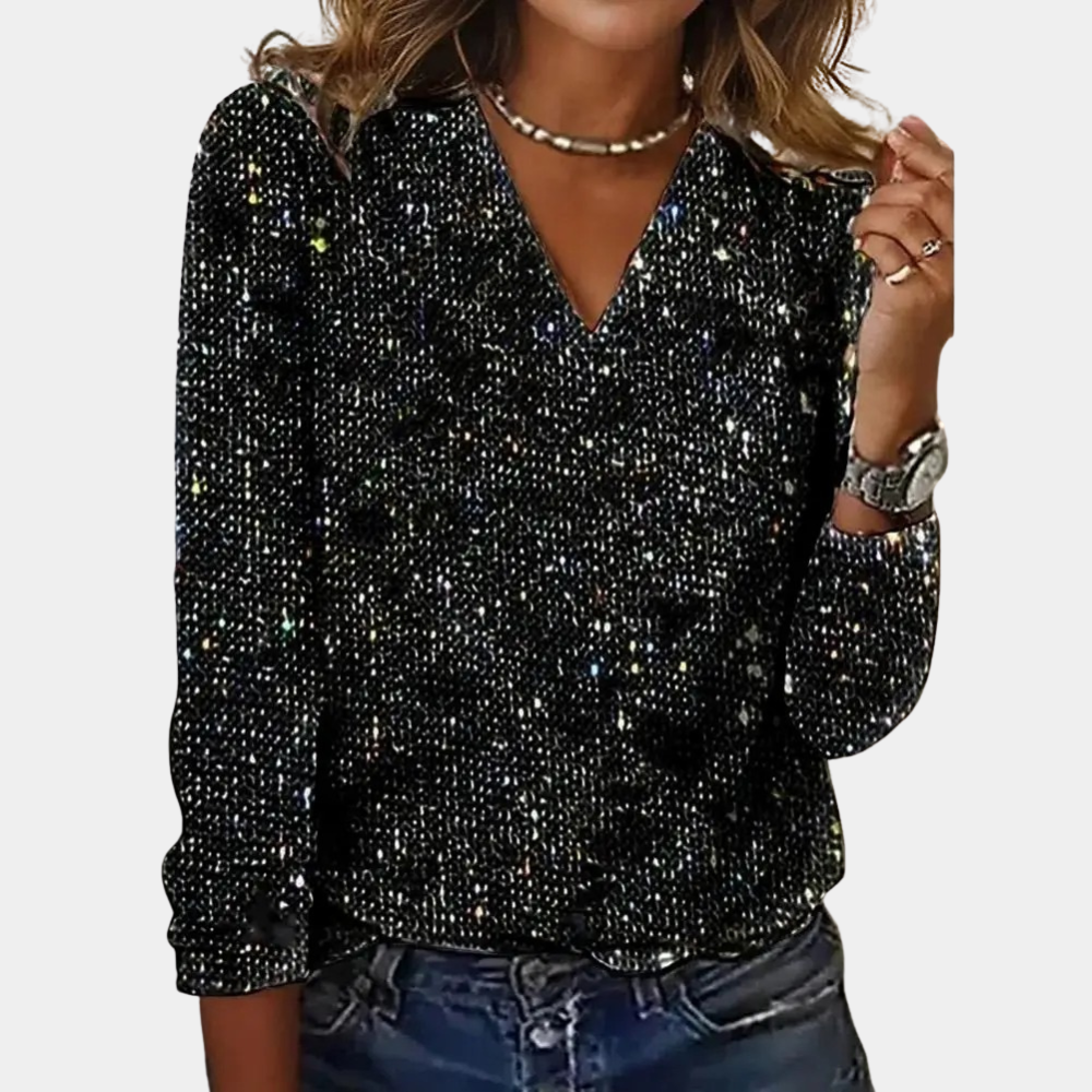 A woman wearing a sparkling V-neck top paired with denim jeans and accessorized with layered necklaces and a watch. The top features a glamorous design, perfect for parties, special occasions, or casual chic outfits.