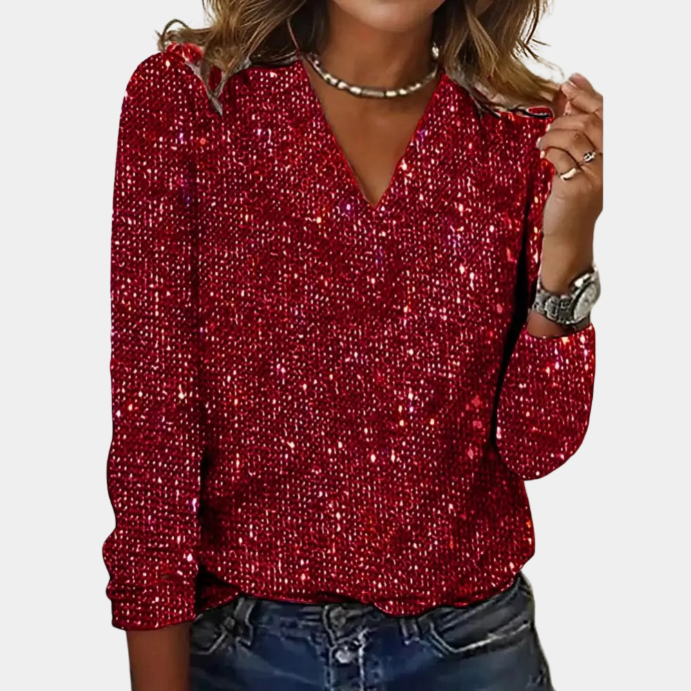 A woman wearing a sparkling V-neck top paired with denim jeans and accessorized with layered necklaces and a watch. The top features a glamorous design, perfect for parties, special occasions, or casual chic outfits.