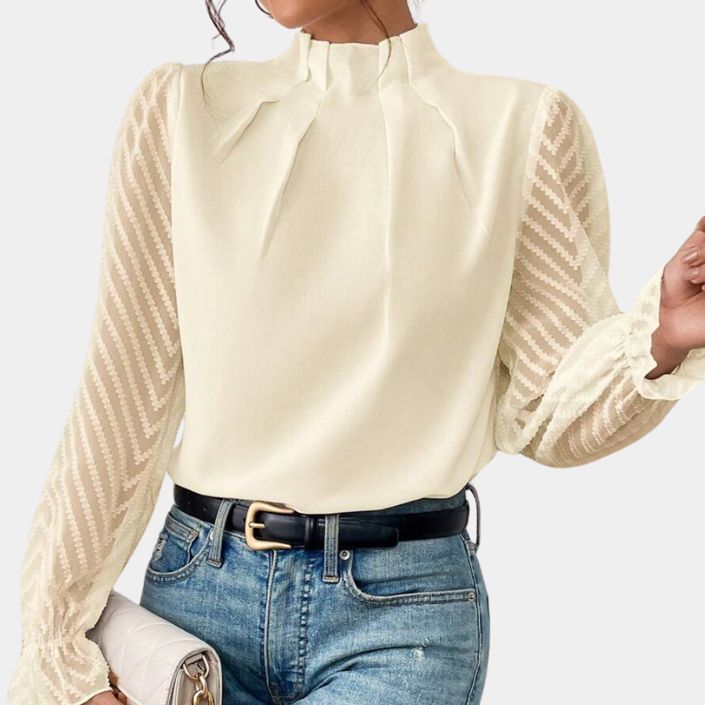 Woman wearing an elegant blouse with a high neckline, pleated front detail, sheer long sleeves with a subtle pattern, and ruffled cuffs, paired with denim jeans for a stylish and sophisticated look.