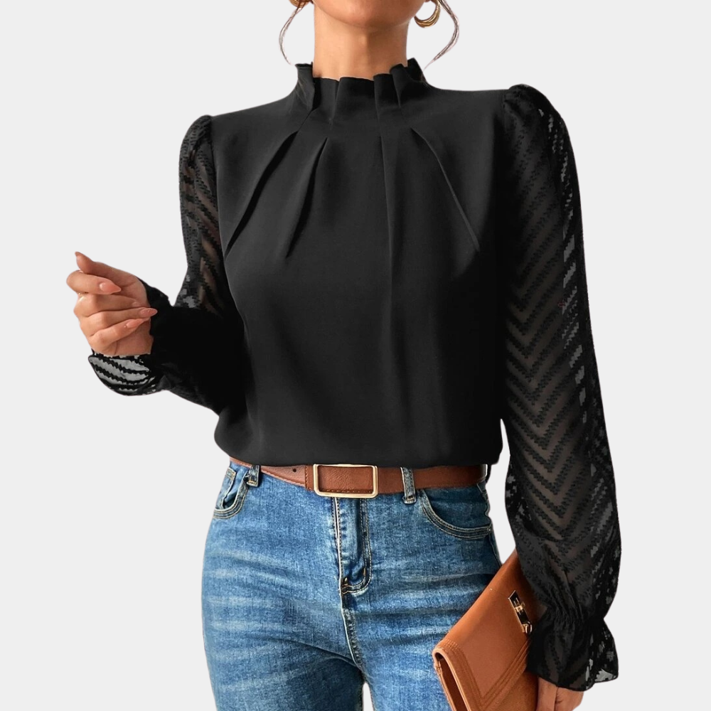 Woman wearing an elegant blouse with a high neckline, pleated front detail, sheer long sleeves with a subtle pattern, and ruffled cuffs, paired with denim jeans for a stylish and sophisticated look.