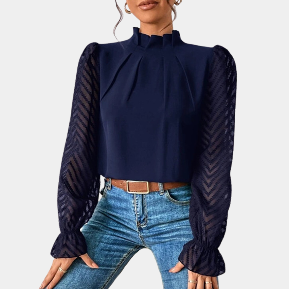 Woman wearing an elegant blouse with a high neckline, pleated front detail, sheer long sleeves with a subtle pattern, and ruffled cuffs, paired with denim jeans for a stylish and sophisticated look.