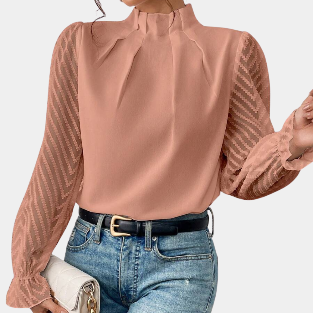 Woman wearing an elegant blouse with a high neckline, pleated front detail, sheer long sleeves with a subtle pattern, and ruffled cuffs, paired with denim jeans for a stylish and sophisticated look.