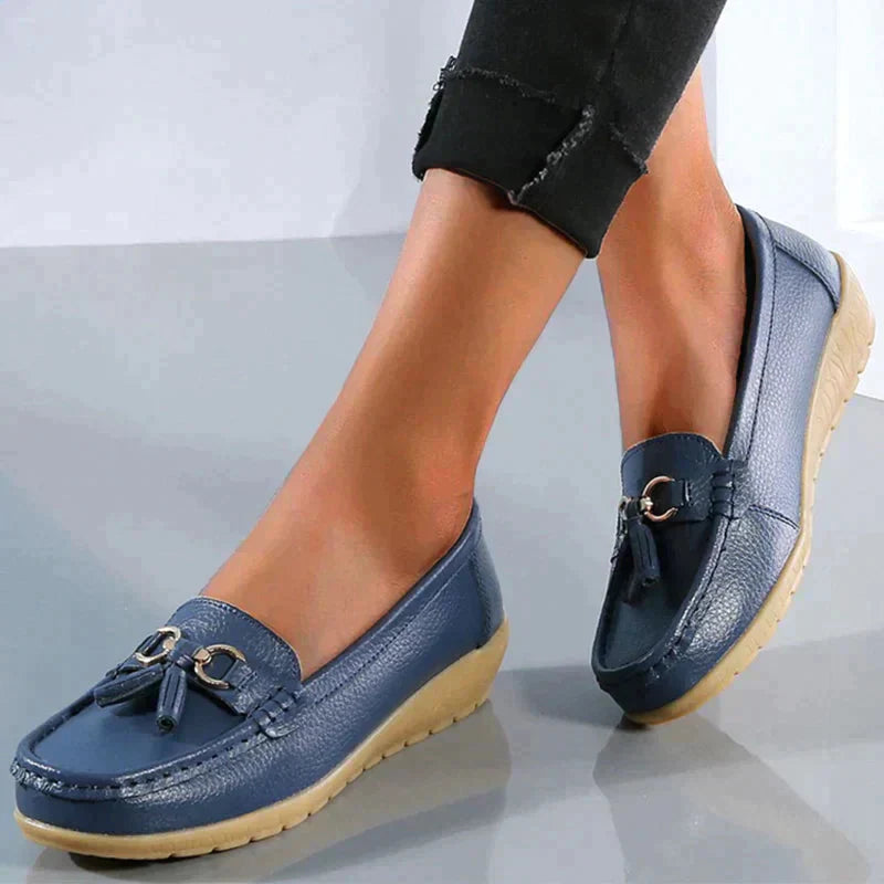 A pair of Grace Women's Classic Loafer Shoes featuring a stylish buckle detail and stitched accents, worn by a person. These loafers combine elegance with comfort, making them suitable for both casual and professional wear.