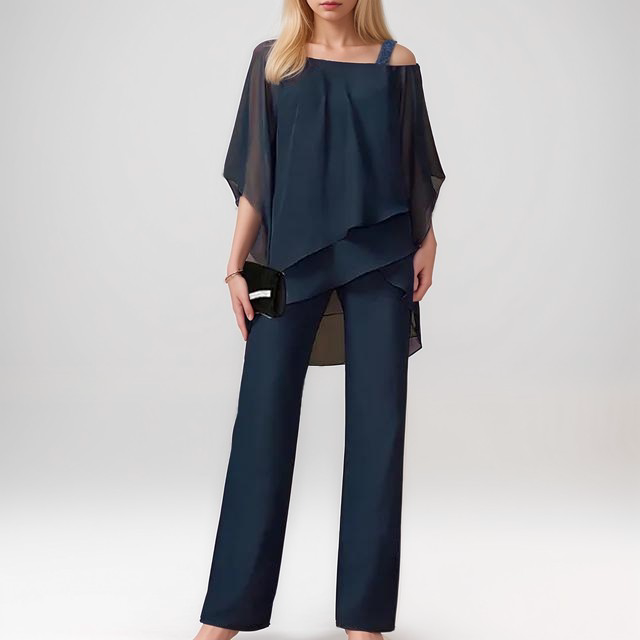 A stylish woman wearing the Sophia | Women's Layered Jumpsuit | Elegant Jumpsuit, featuring a flowing layered top and tailored wide-leg pants, accessorized with a clutch bag and heels, perfect for formal or special occasions.