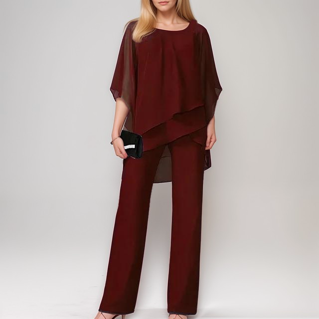 A stylish woman wearing the Sophia | Women's Layered Jumpsuit | Elegant Jumpsuit, featuring a flowing layered top and tailored wide-leg pants, accessorized with a clutch bag and heels, perfect for formal or special occasions.