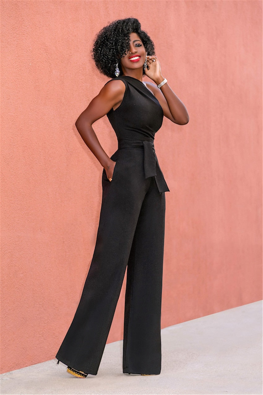 A woman wearing a stylish one-shoulder jumpsuit with a tie waist and wide-leg design, creating an elegant and modern look. The outfit is perfect for formal occasions or evening events, combining sophistication with a bold fashion statement.