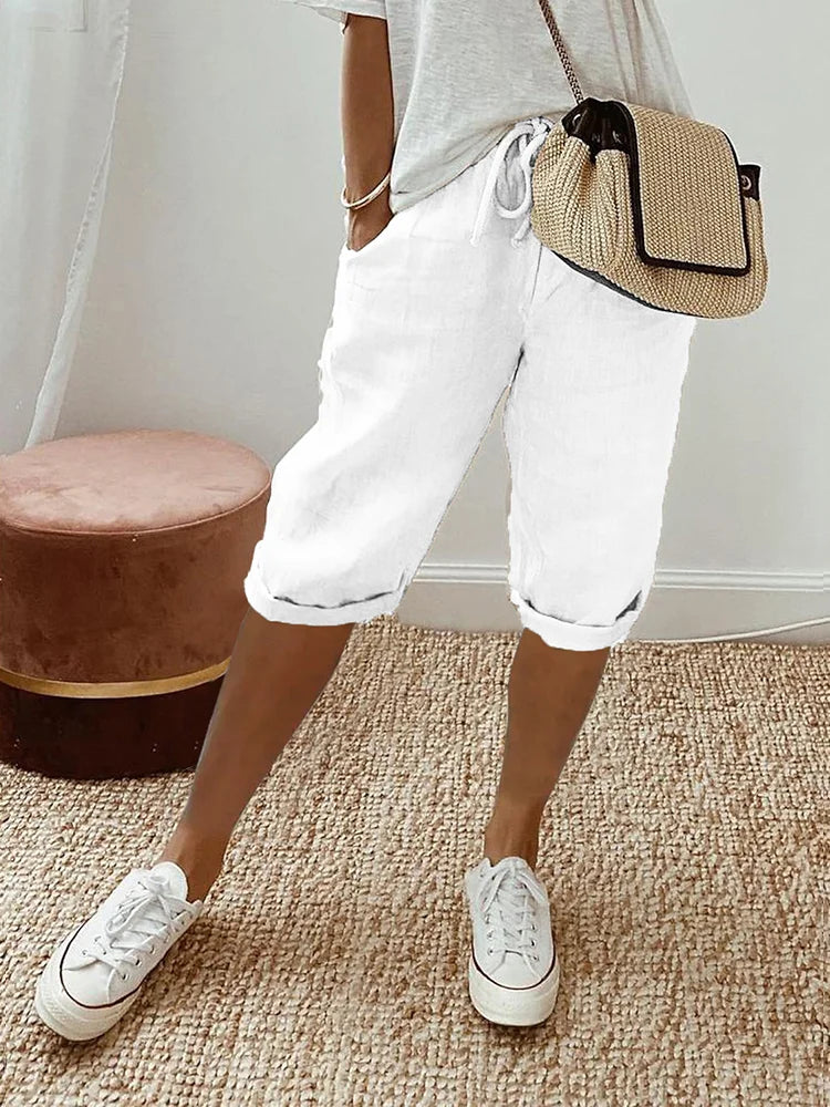 Women's relaxed-fit shorts paired with casual sneakers and a stylish woven bag, perfect for a comfortable and chic everyday look.