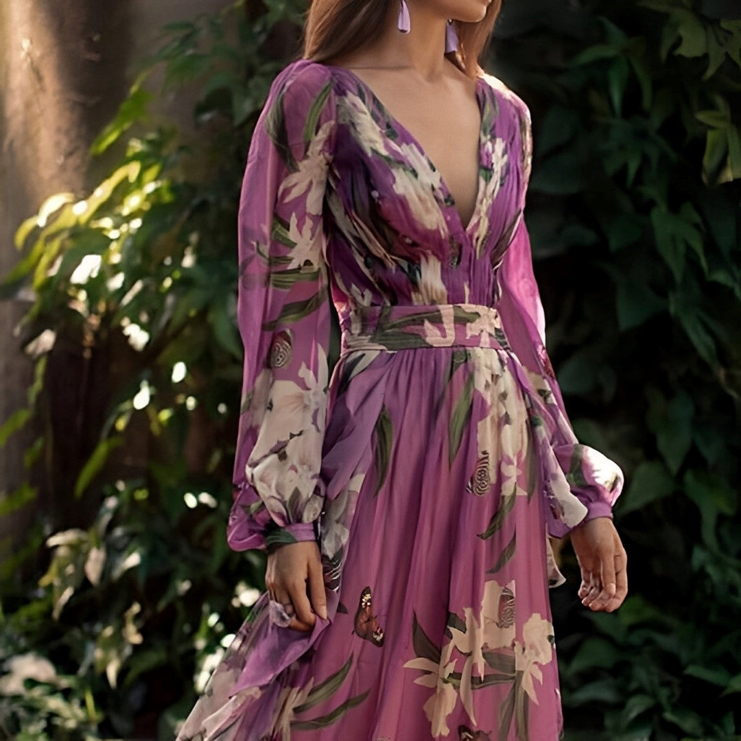 Woman wearing the Elara Women's Floral Chiffon Dress, an elegant long dress with a delicate floral design, flowy long sleeves, and a fitted waist, posing gracefully outdoors amidst lush greenery.
