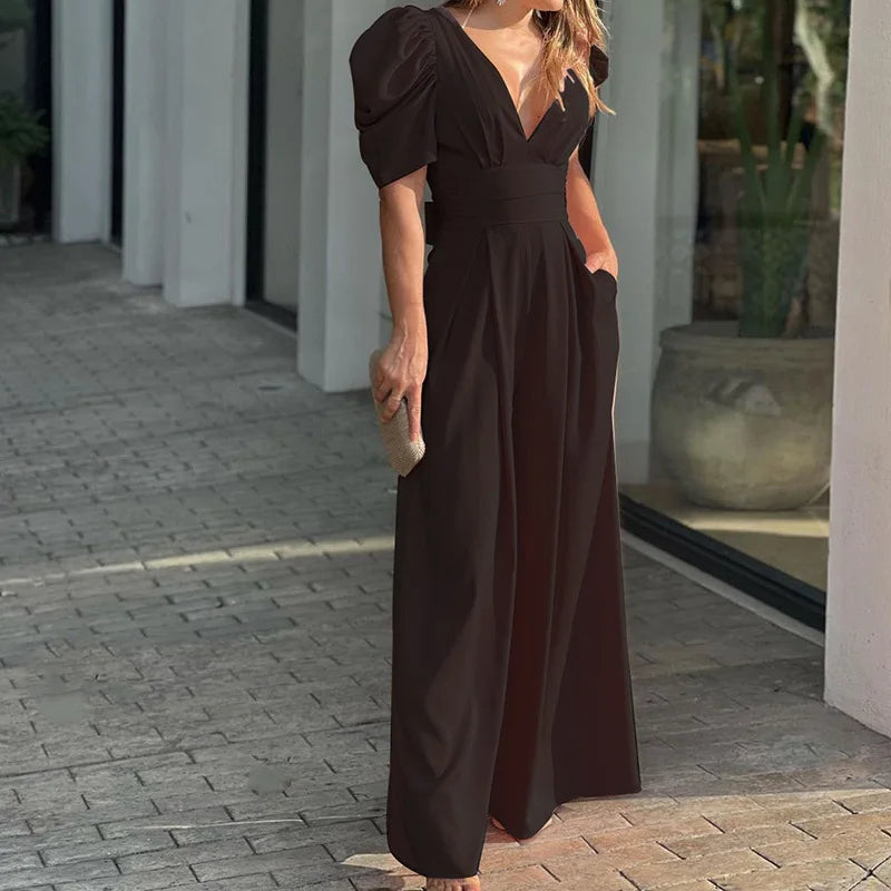 Woman wearing the Vivian Women's Puff Sleeve Maxi Dress, a V-neck dress with elegant puff sleeves and a flowing maxi silhouette, holding a small clutch bag and standing stylishly on a paved walkway.