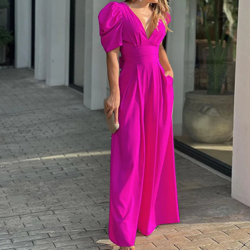 Woman wearing the Vivian Women's Puff Sleeve Maxi Dress, a V-neck dress with elegant puff sleeves and a flowing maxi silhouette, holding a small clutch bag and standing stylishly on a paved walkway.