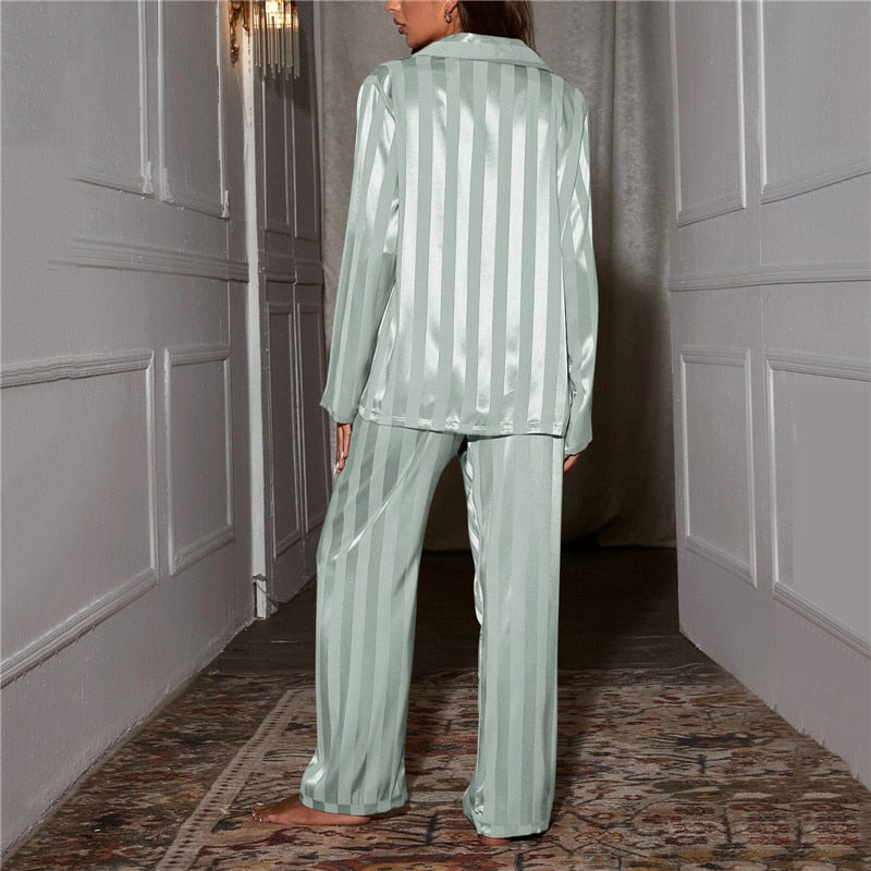 A woman wearing a luxurious satin pajama set featuring a button-up shirt and relaxed-fit pants, perfect for comfortable and elegant loungewear or sleepwear. Ideal for cozy nights or stylish relaxation at home.