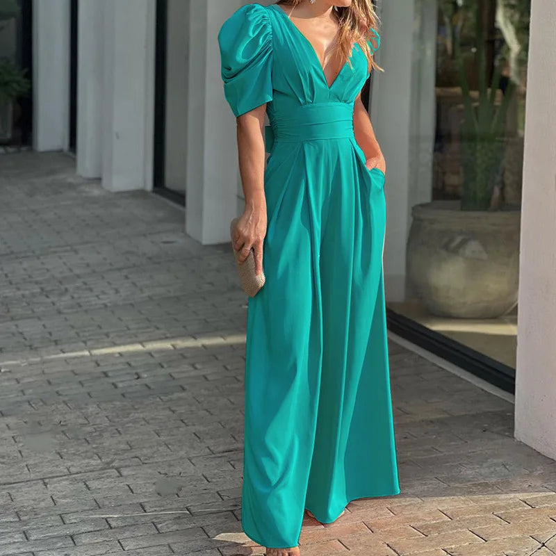 Woman wearing the Vivian Women's Puff Sleeve Maxi Dress, a V-neck dress with elegant puff sleeves and a flowing maxi silhouette, holding a small clutch bag and standing stylishly on a paved walkway.