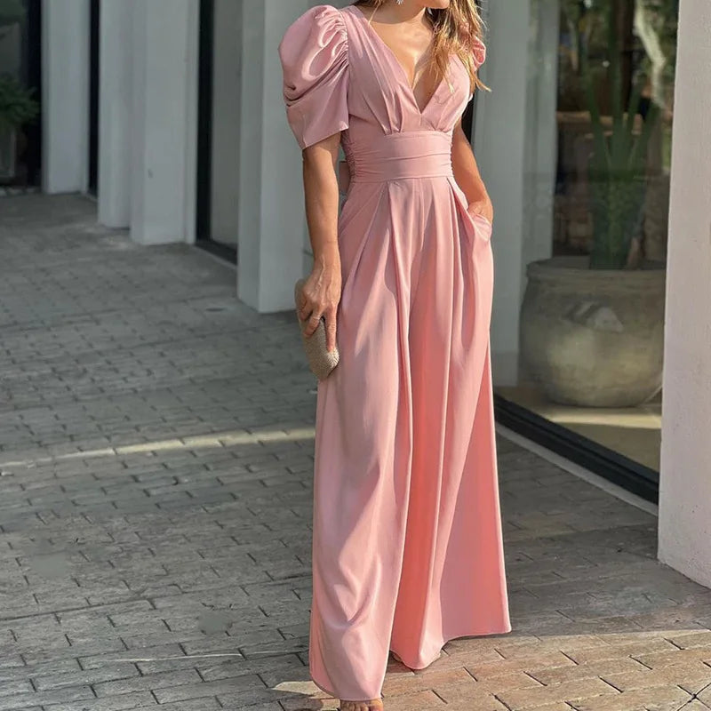 Woman wearing the Vivian Women's Puff Sleeve Maxi Dress, a V-neck dress with elegant puff sleeves and a flowing maxi silhouette, holding a small clutch bag and standing stylishly on a paved walkway.