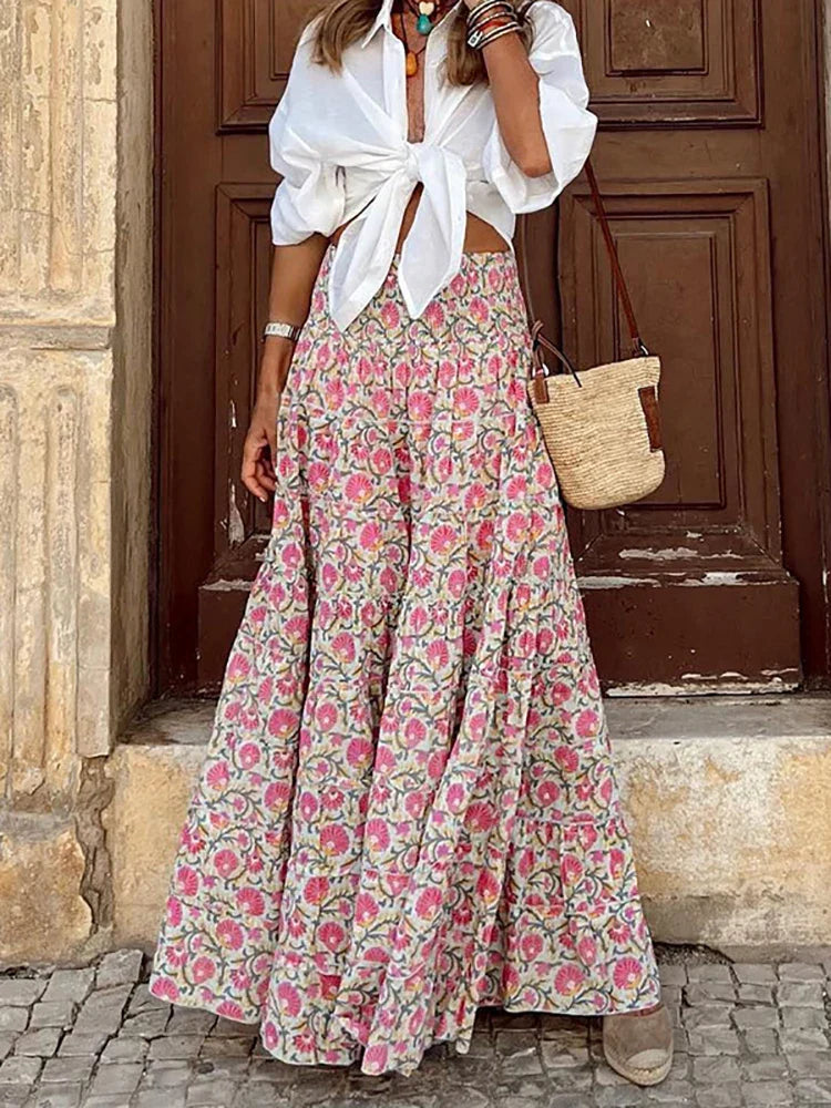 Stylish woman wearing a flowy maxi skirt with a bohemian pattern, paired with a tied blouse and accessories, showcasing a chic and effortless outfit perfect for casual and festive occasions.