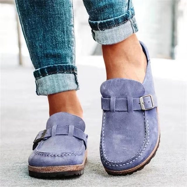 Women's stylish loafers with a comfortable design, featuring a slip-on style and elegant buckle detail, paired with rolled-up denim jeans for a casual look.