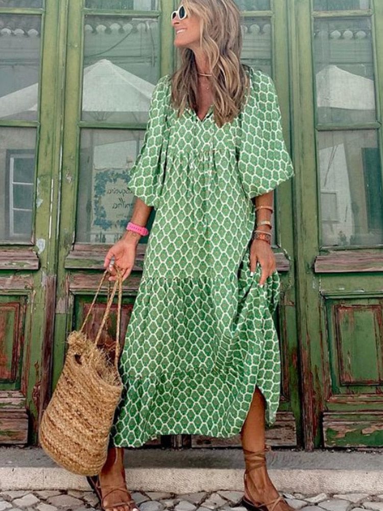 Woman wearing the Emma | Boho Chic Flowing Midi Dress, standing in front of a vintage-style green door, holding a woven straw bag, and accessorized with bracelets and sunglasses. The dress features a relaxed, flowing fit with a bohemian vibe.