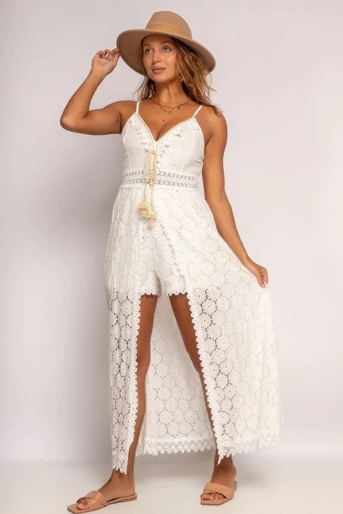 A woman wearing the Lily Women's Lace Overlay Dress, a boho-inspired romper dress with a flowing lace overlay and adjustable straps, styled with a wide-brimmed hat and flat sandals. Perfect for casual outings, beach days, and summer festivals, combining elegance with a relaxed bohemian look.