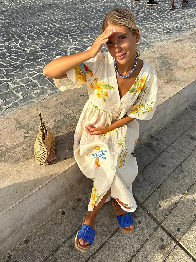 A fashionable woman taking a mirror selfie outdoors, wearing the Sophia | Women's Printed Midi Dress | Puff Sleeve Dress, styled with a woven bag, matching accessories, and flat sandals, showcasing the dress's elegant design and comfortable fit.