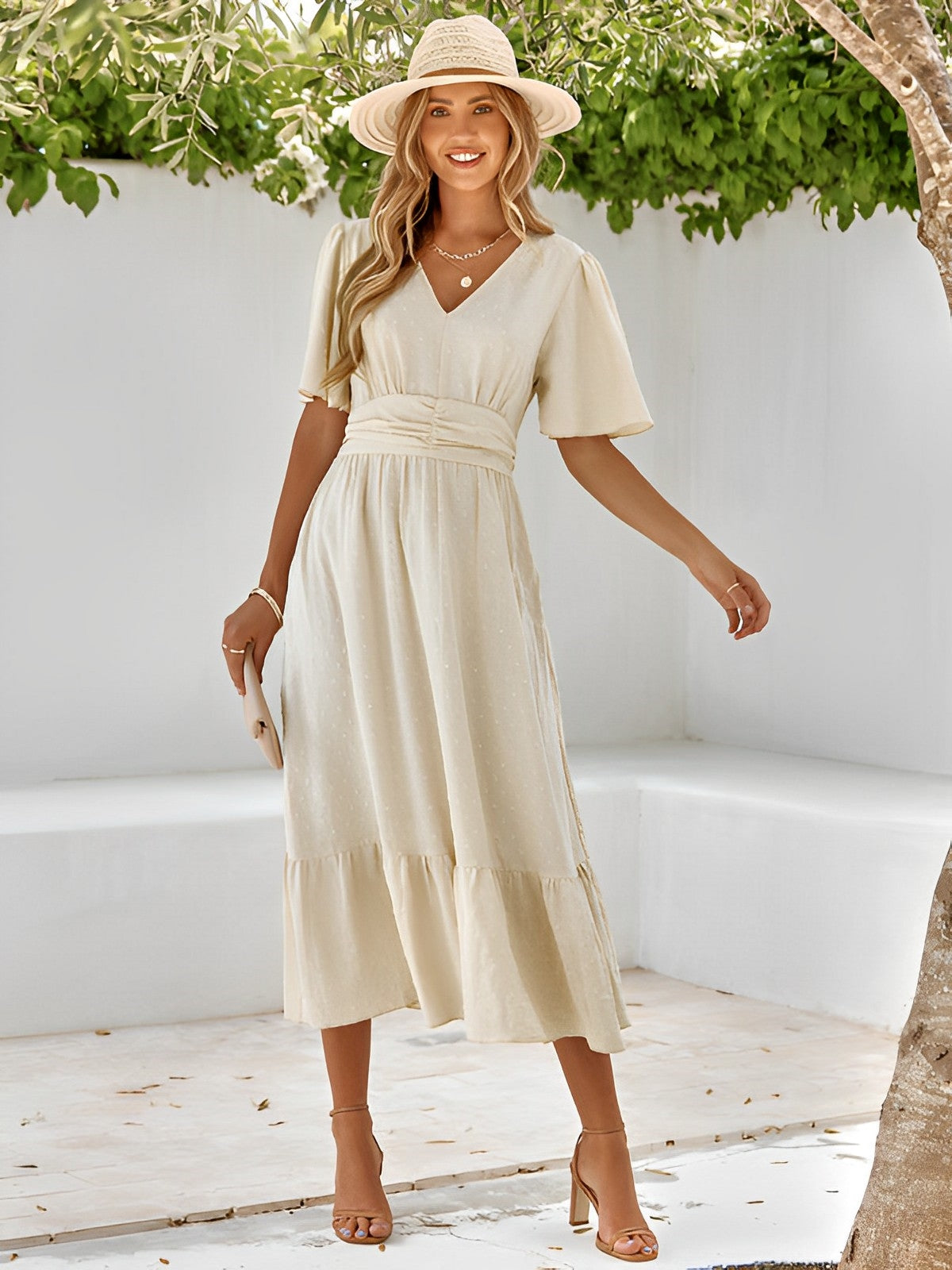 Woman wearing the Sophie | Elegant V-Neck Midi Dress with a flowing skirt and cinched waist, styled with a wide-brimmed hat and heels, perfect for an effortlessly chic and sophisticated look at any event.