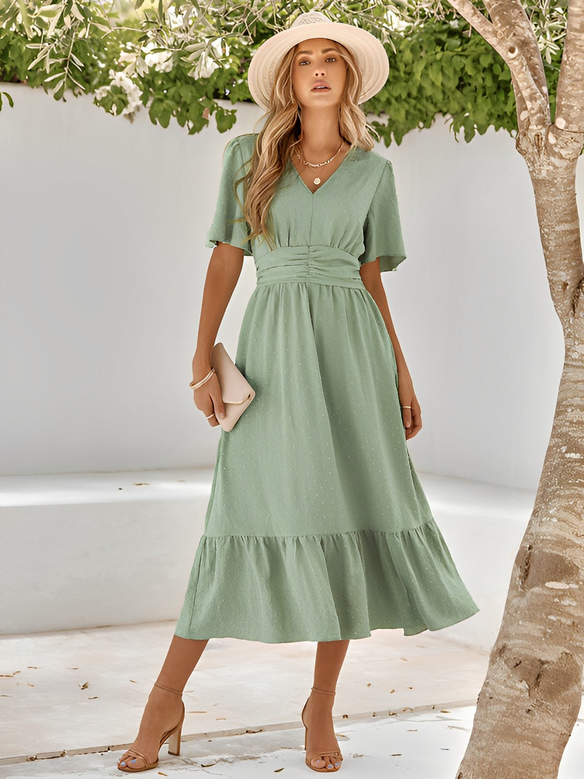 Woman wearing the Sophie | Elegant V-Neck Midi Dress with a flowing skirt and cinched waist, styled with a wide-brimmed hat and heels, perfect for an effortlessly chic and sophisticated look at any event.