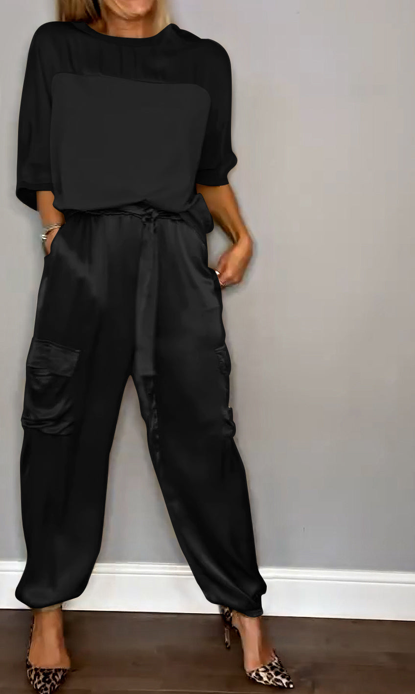Image showcasing a stylish satin jumpsuit with a relaxed fit, featuring a belt at the waist and practical side pockets, perfect for an elegant yet comfortable look.