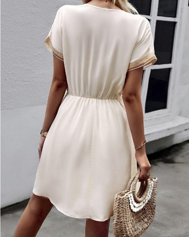 Woman wearing the Leah | Boho V-Neck Drawstring Dress with a relaxed fit and delicate detailing around the neckline. The dress is styled with a cinched waist, achieved through a drawstring, and paired with layered necklaces and a stylish handbag for a chic bohemian look.