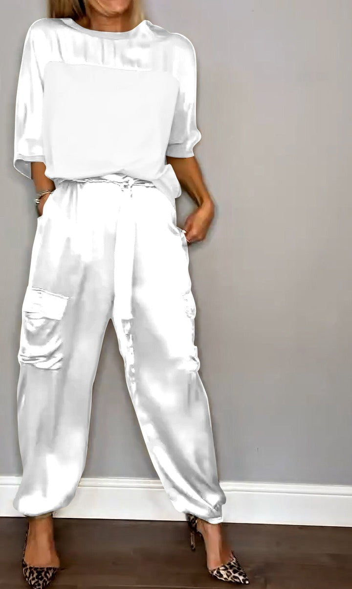 Image showcasing a stylish satin jumpsuit with a relaxed fit, featuring a belt at the waist and practical side pockets, perfect for an elegant yet comfortable look.