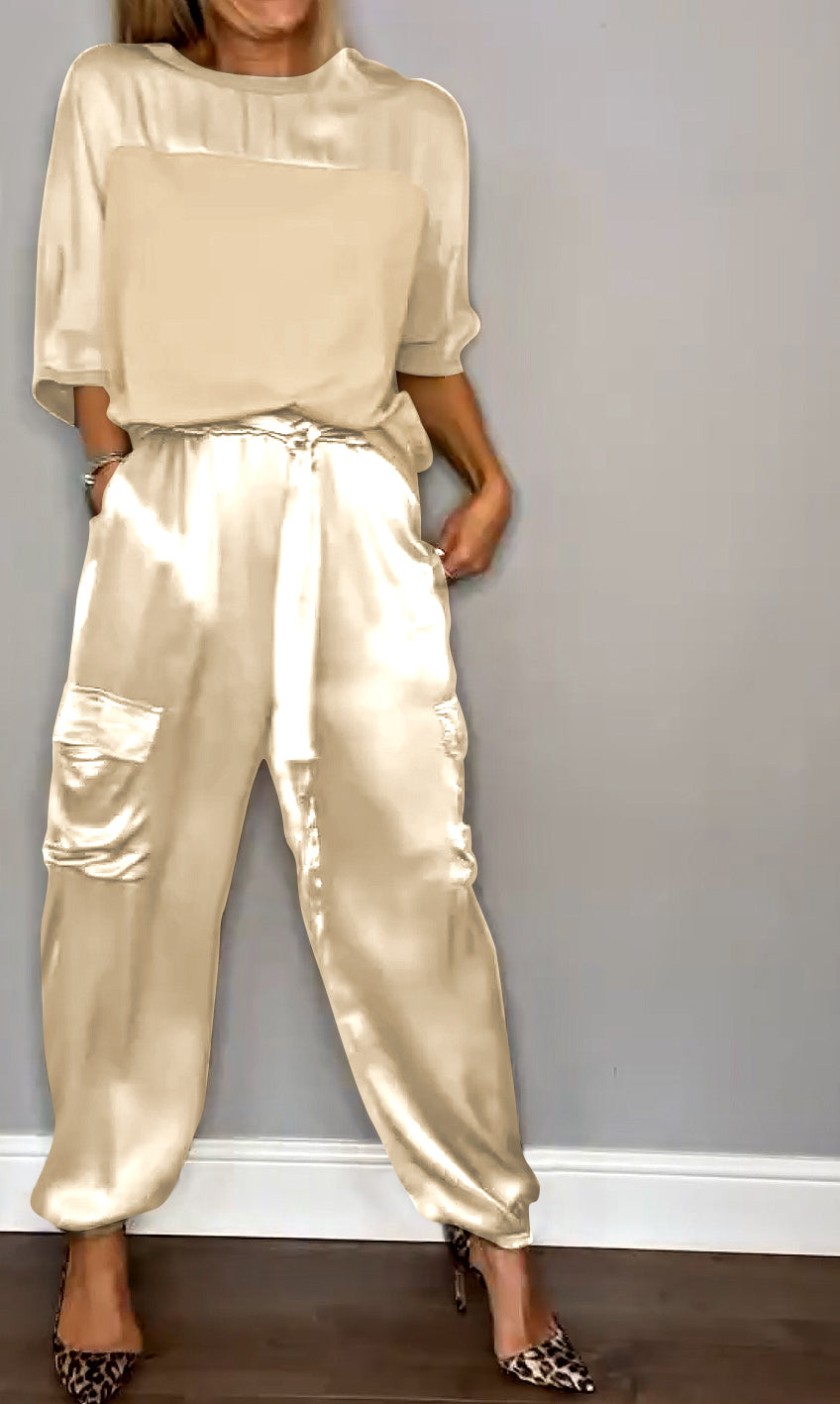 Image showcasing a stylish satin jumpsuit with a relaxed fit, featuring a belt at the waist and practical side pockets, perfect for an elegant yet comfortable look.