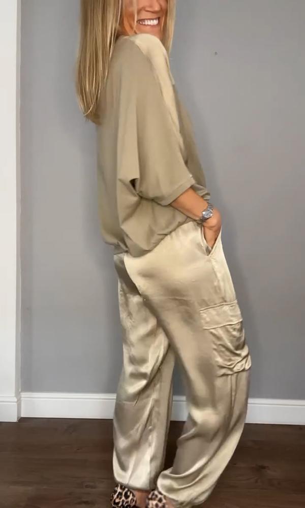 Image showcasing a stylish satin jumpsuit with a relaxed fit, featuring a belt at the waist and practical side pockets, perfect for an elegant yet comfortable look.