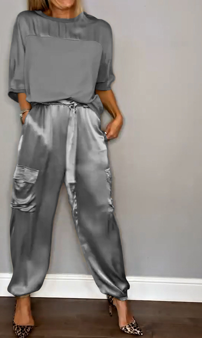 Image showcasing a stylish satin jumpsuit with a relaxed fit, featuring a belt at the waist and practical side pockets, perfect for an elegant yet comfortable look.