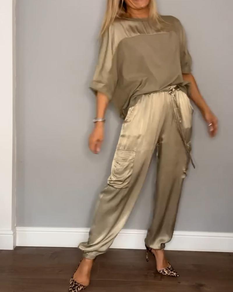 Image showcasing a stylish satin jumpsuit with a relaxed fit, featuring a belt at the waist and practical side pockets, perfect for an elegant yet comfortable look.