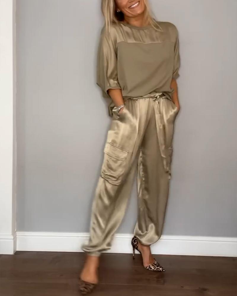 Image showcasing a stylish satin jumpsuit with a relaxed fit, featuring a belt at the waist and practical side pockets, perfect for an elegant yet comfortable look.