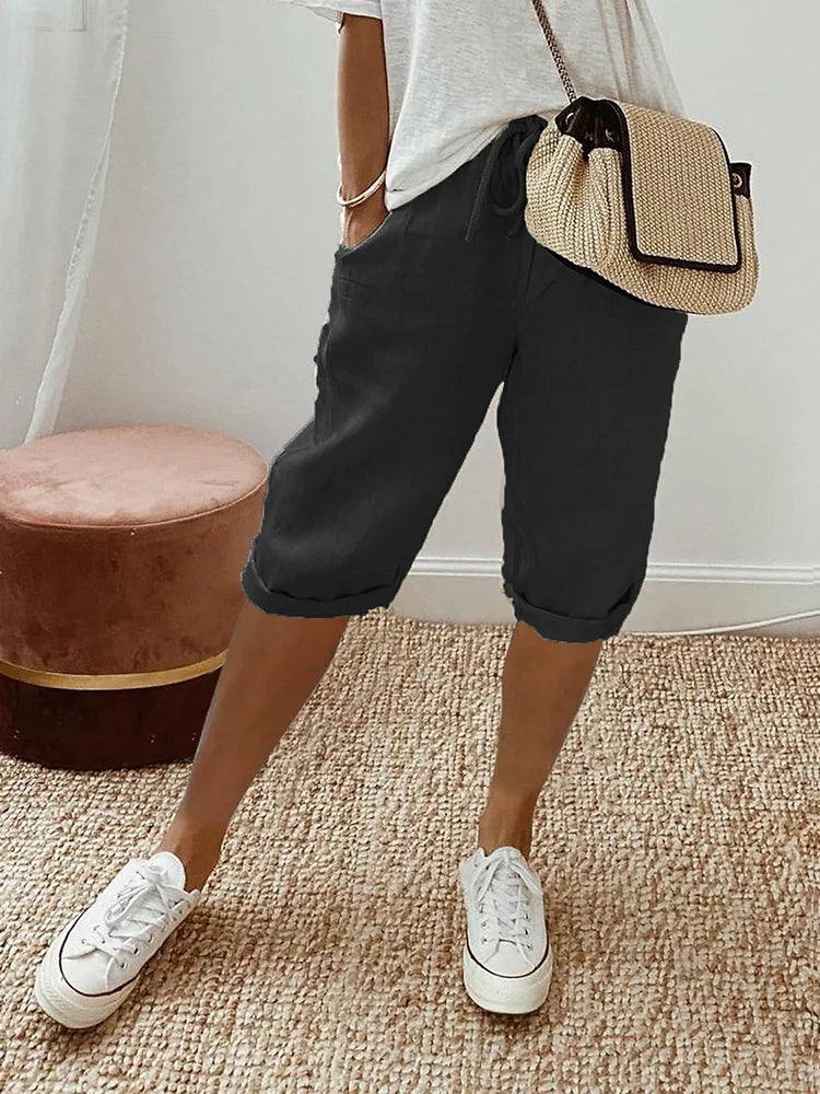 Women's relaxed-fit shorts paired with casual sneakers and a stylish woven bag, perfect for a comfortable and chic everyday look.