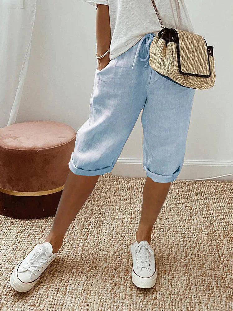 Women's relaxed-fit shorts paired with casual sneakers and a stylish woven bag, perfect for a comfortable and chic everyday look.
