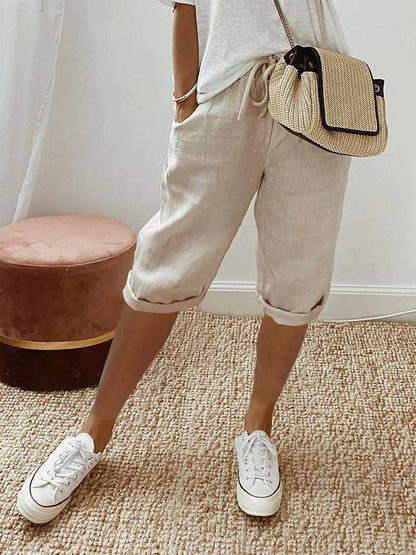 Women's relaxed-fit shorts paired with casual sneakers and a stylish woven bag, perfect for a comfortable and chic everyday look.