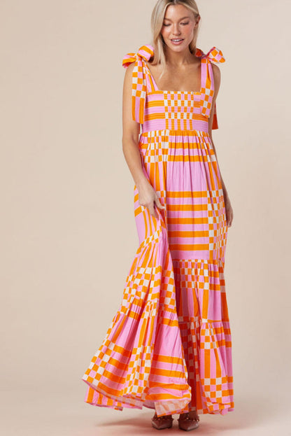 A woman wearing a stylish checkered maxi dress with a flowing skirt and bow-tie shoulder straps, creating a bold and eye-catching look. The dress exudes a statement style, perfect for casual outings or special occasions.