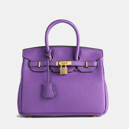 Image showing a woman holding an elegant handbag with a sleek design, featuring gold hardware and a structured shape, paired with casual attire for a stylish, sophisticated look.
