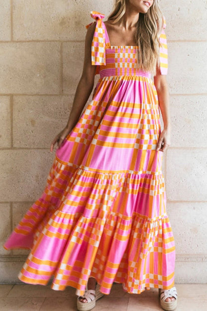 A woman wearing a stylish checkered maxi dress with a flowing skirt and bow-tie shoulder straps, creating a bold and eye-catching look. The dress exudes a statement style, perfect for casual outings or special occasions.