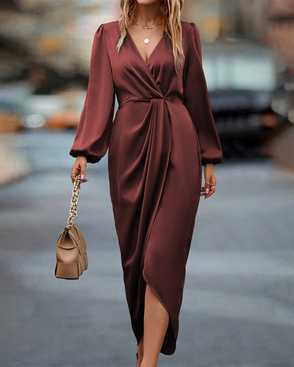A woman wearing a long wrap dress with elegant long sleeves, walking confidently on a city street. The dress features a flattering wrap design that cinches at the waist, creating a graceful silhouette perfect for both formal and casual occasions. She carries a stylish handbag to complete the look.