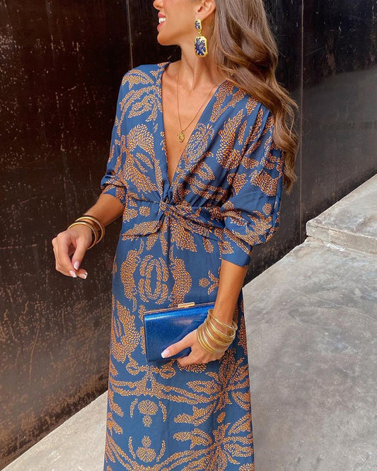 A close-up of a woman wearing the Nina Women's Elegant Wrap Dress, featuring a bold pattern and flattering wrap design with a deep V-neckline. The dress showcases intricate patterns and a knot detail at the waist, creating a sophisticated and stylish look suitable for special occasions.