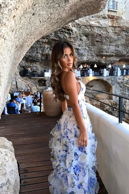 An elegant maxi dress featuring a ruffled design and a flattering silhouette, perfect for special occasions or evening wear. The model is styled on a scenic terrace, showcasing the sophisticated and graceful appeal of the dress.