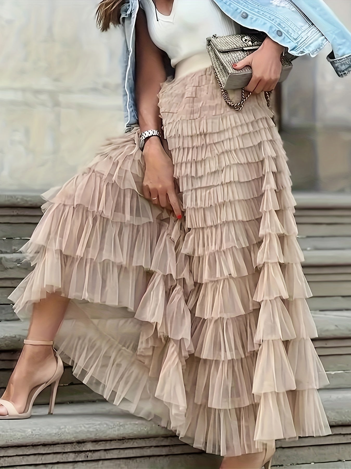 Woman wearing the Sophie Women's Layered Tulle Skirt, a ruffled skirt with multiple soft layers, creating a flowing and voluminous look, styled with a sleeveless top and accessories, standing on steps outdoors.