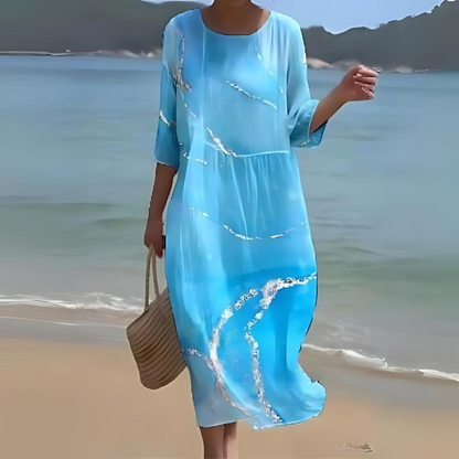 Elegant women's floral dress worn on the beach, paired with a woven handbag, perfect for summer outings and casual strolls.