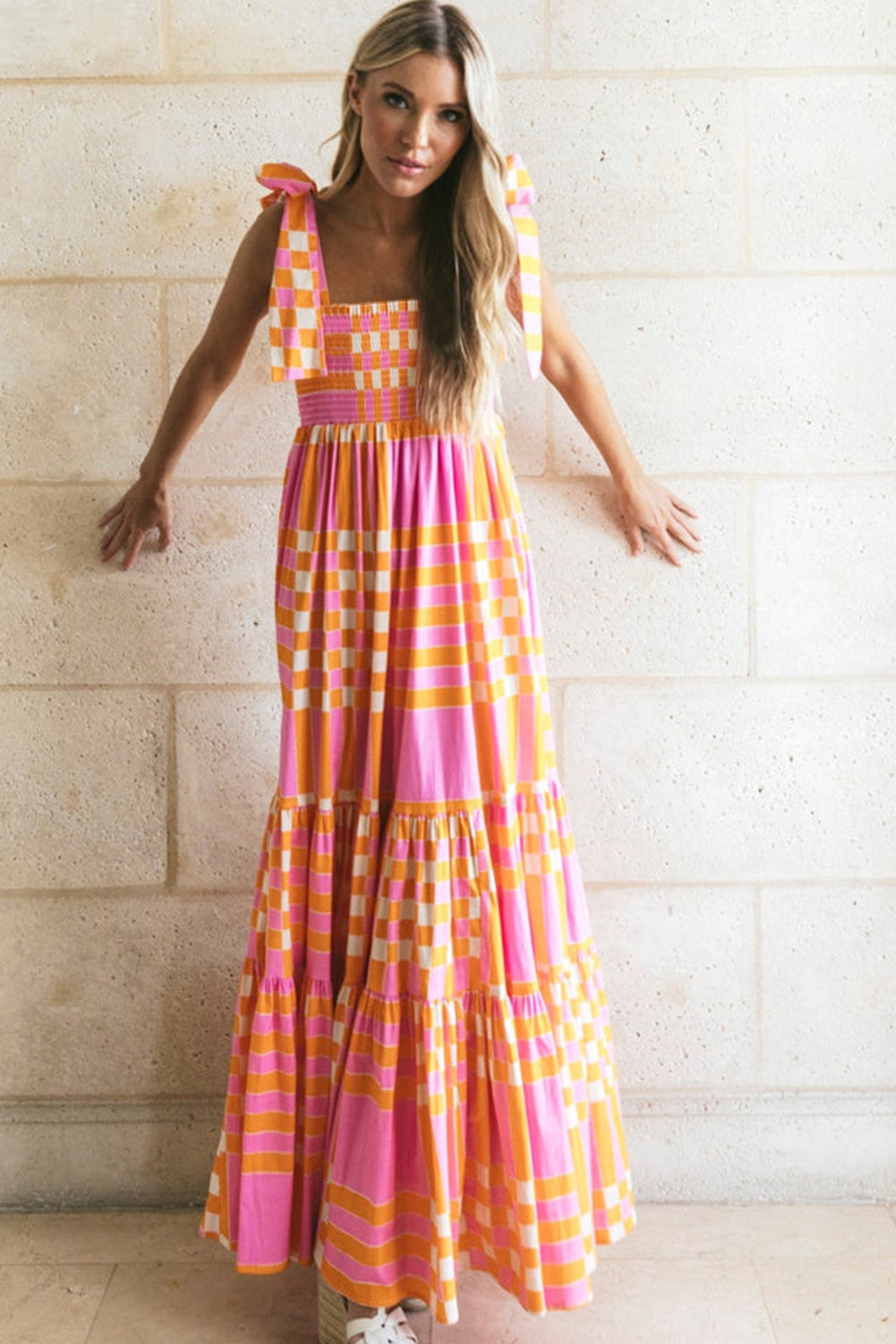 A woman wearing a stylish checkered maxi dress with a flowing skirt and bow-tie shoulder straps, creating a bold and eye-catching look. The dress exudes a statement style, perfect for casual outings or special occasions.