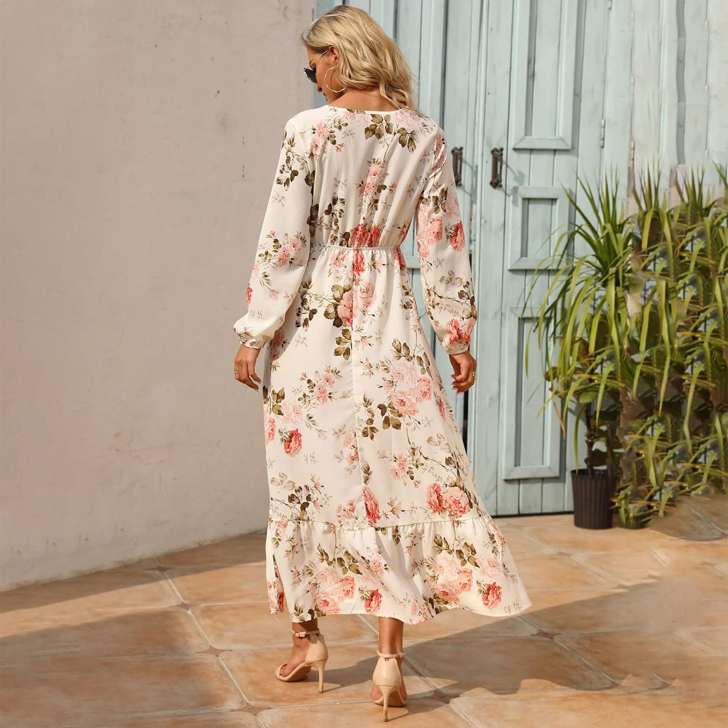 Woman wearing the Camilla Women's Floral Maxi Dress, a long dress with a flowy silhouette and elegant floral design, styled with long sleeves and paired with strappy heels, standing outdoors in a sunny, stylish setting.