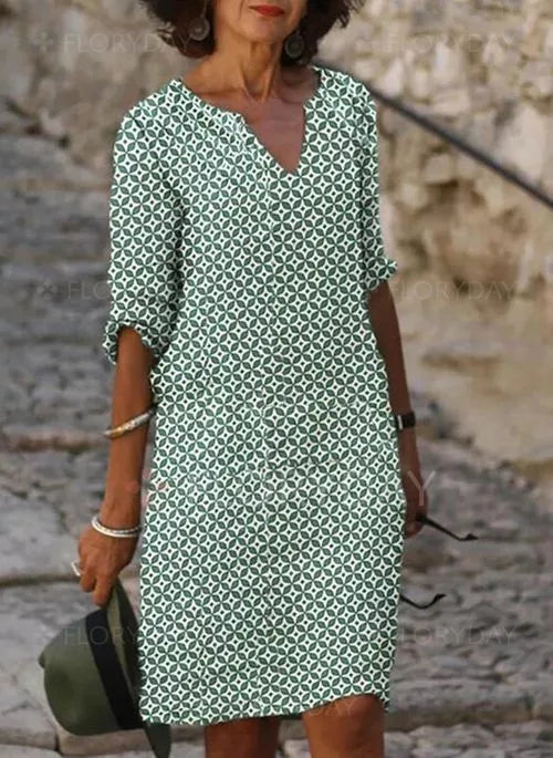 A woman wearing the Elena Women's Printed Shift Dress with a classic V-neck design and relaxed fit. The dress features a stylish printed pattern, perfect for casual outings or semi-formal occasions, offering an effortlessly chic look.